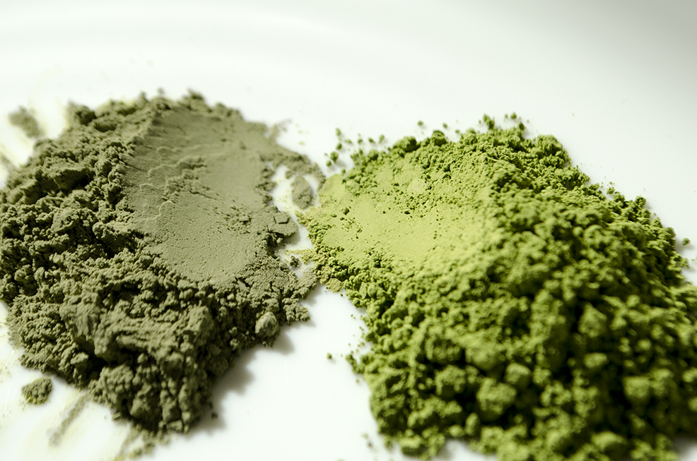 Two piles of matcha, on the right hand side is a vibrant glossy emerald green matcha and on the left hand side is a dull grey looking matcha.