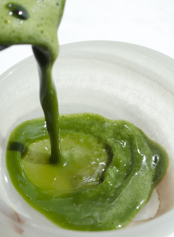 emeral green matcha pouring into a white stone cup